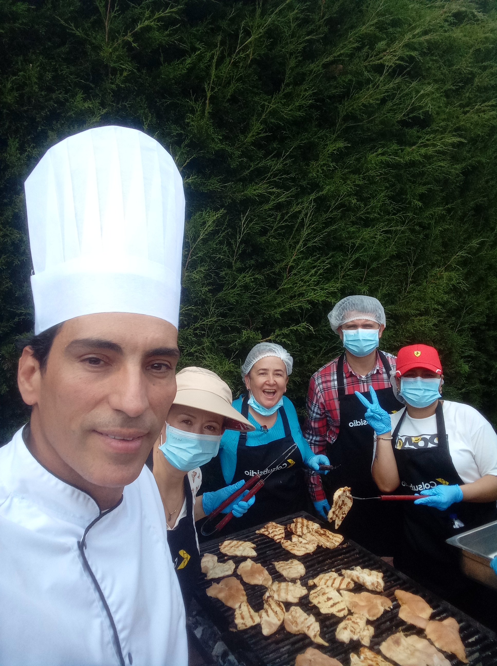 Equipo celebrando con chef frente a las brasas
